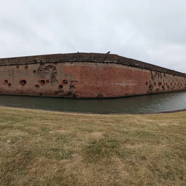 Damaged exterior wall with moat in front.